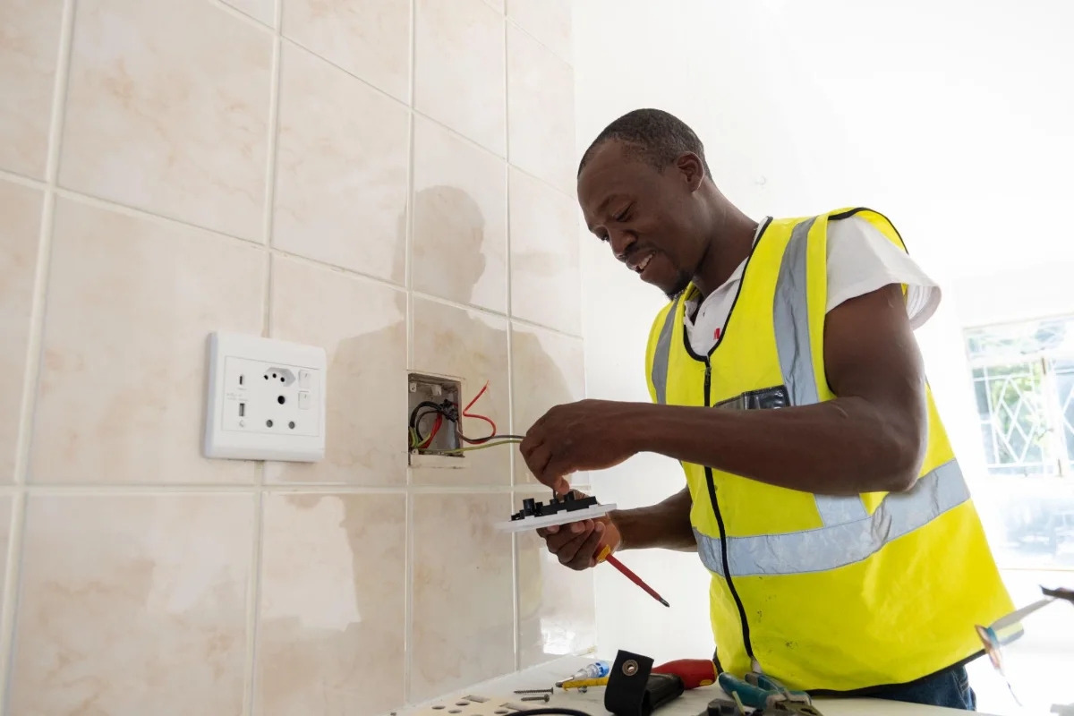 Électricien réparant une prise murale